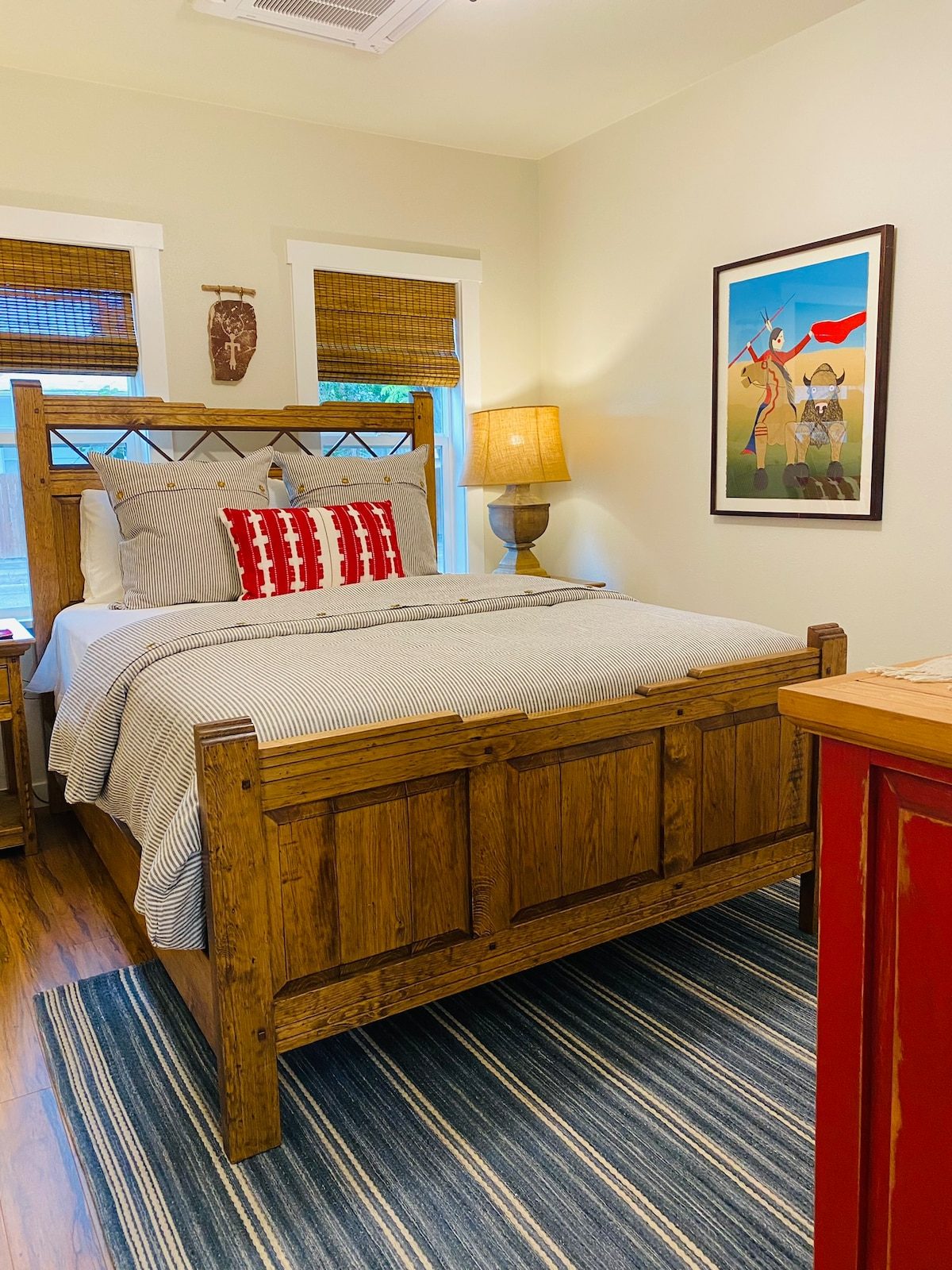 Bedroom with a rustic wood bed, red accent pillows and framed art
