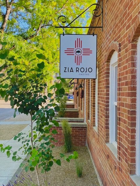 Zia Rojo Casitas hanging sign on a red-brick building